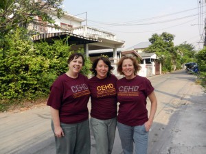 Three women linking arms on a Thai road