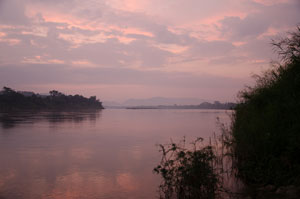 Mekong River landscape under a pink sky at sunset, mountains in the distance