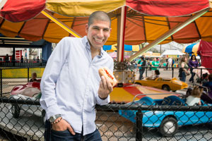 Smiling Joe Zerka holds a hot dog at an amusement park