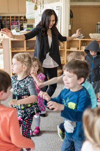 Teacher Almas Merchant surround by children in a movement game