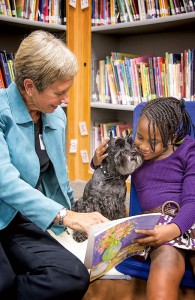 A student reads to Louise Botko and Fury, the literacy dog.