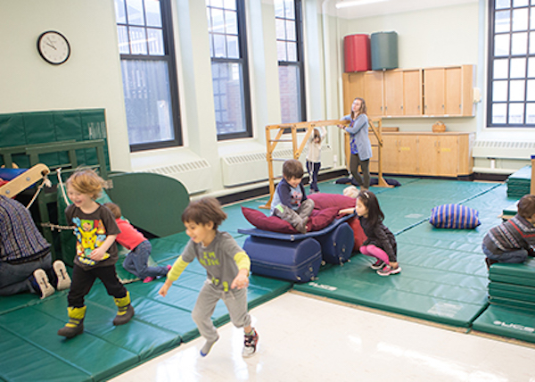 Photo: Students explore physical and pretend play on mats and climbing structures in a lab school classroom.