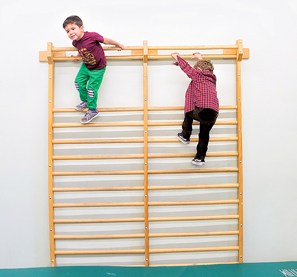 Photo: Two students play on a climbing wall in one of the lab school's classrooms.