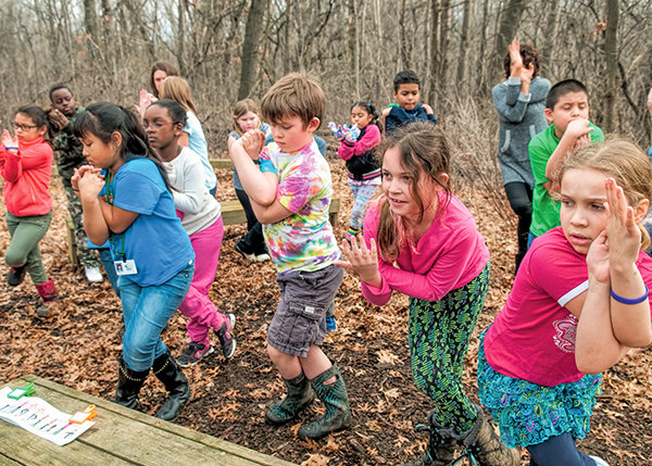 Photo: A group of students practices yoga poses in the woods outside of their school.