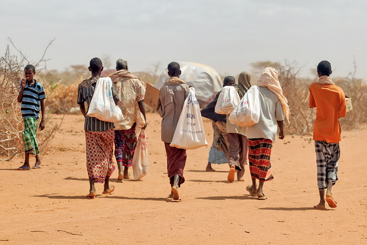 A group of refugees walk with their belongings. Refugees are forced to flee their home countries because of persecution, war, or violence. Somalia was home to large numbers arriving in Minnesota in recent years, many after stays in refugee camps in Kenya.