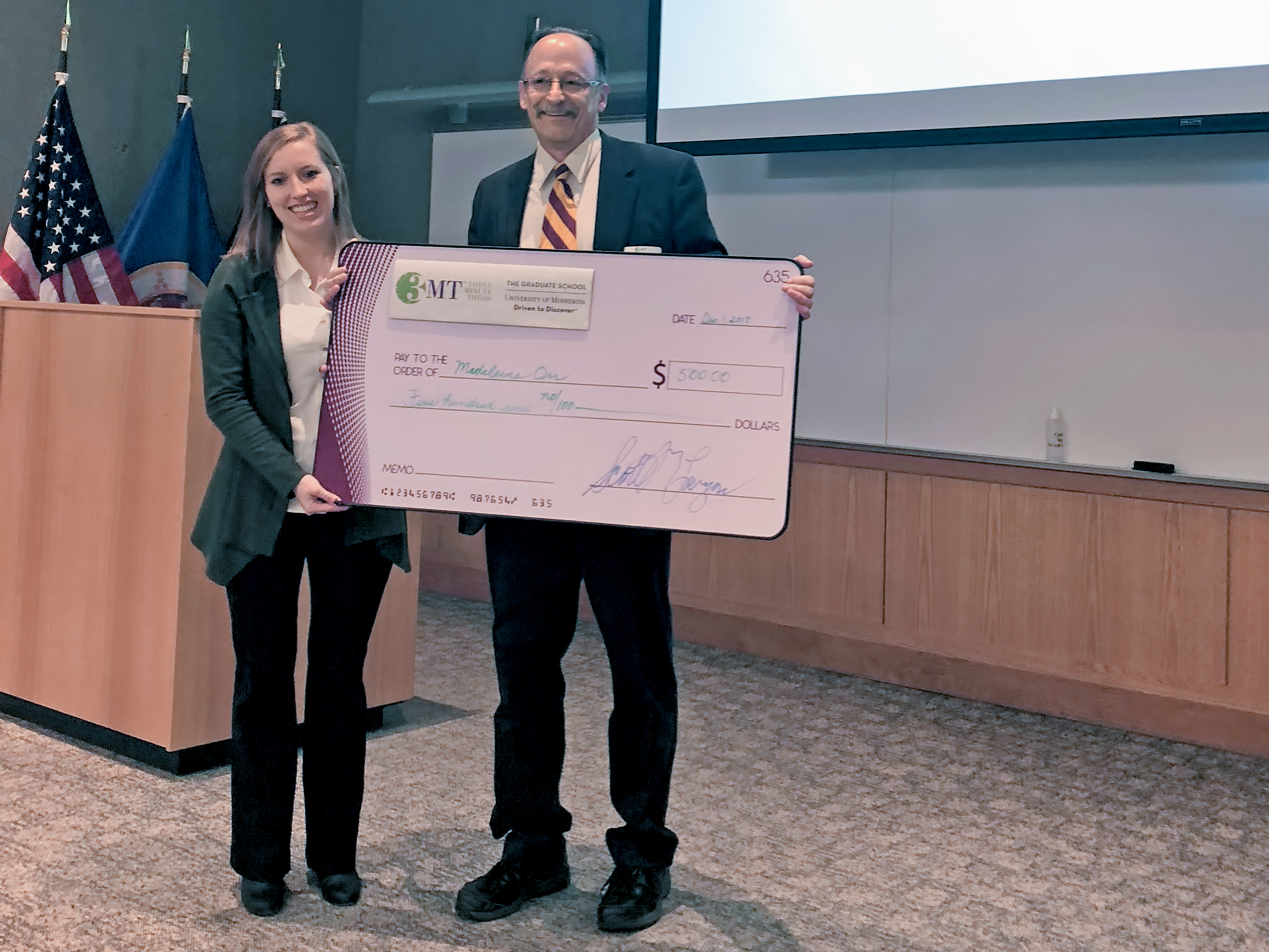 3MT winner Madeline Orr accepted a check from Graduate School dean Scott Lanyon