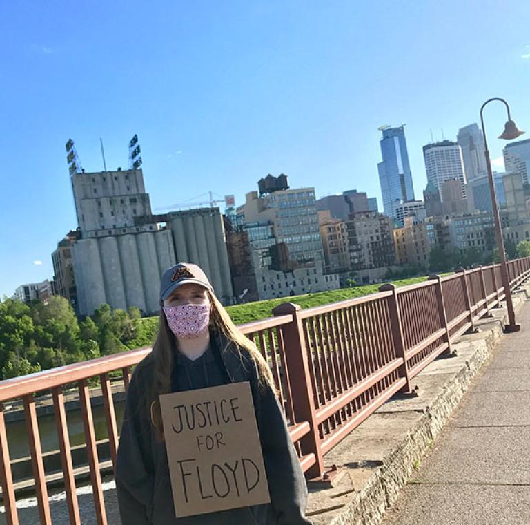 Person holding a 'Justice for Floyd' sign on a bridge