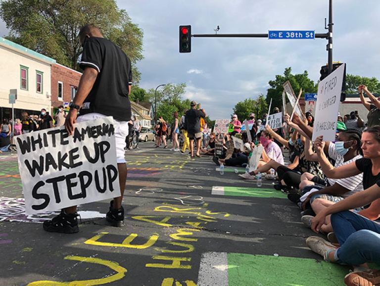 Protestors holding signs, sit in the street