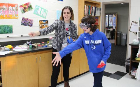 Graduate student demonstrates how to throw a bean bag