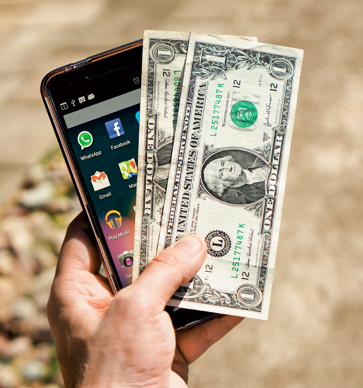 Photo: A hand holding money and a smartphone