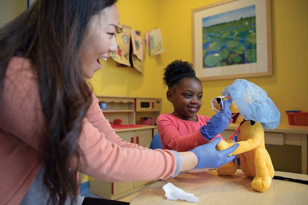 A certified child life specialist engaged in medical play with a patient.