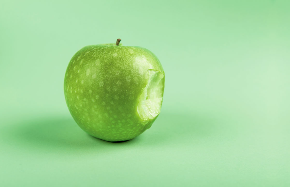 Photo of a Granny Smith (green) apple with a bite taken out of it.