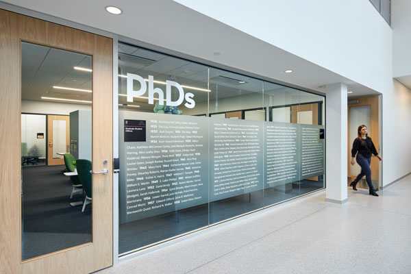 A transparent wall inscribed with the names of all the institute’s PhD graduates